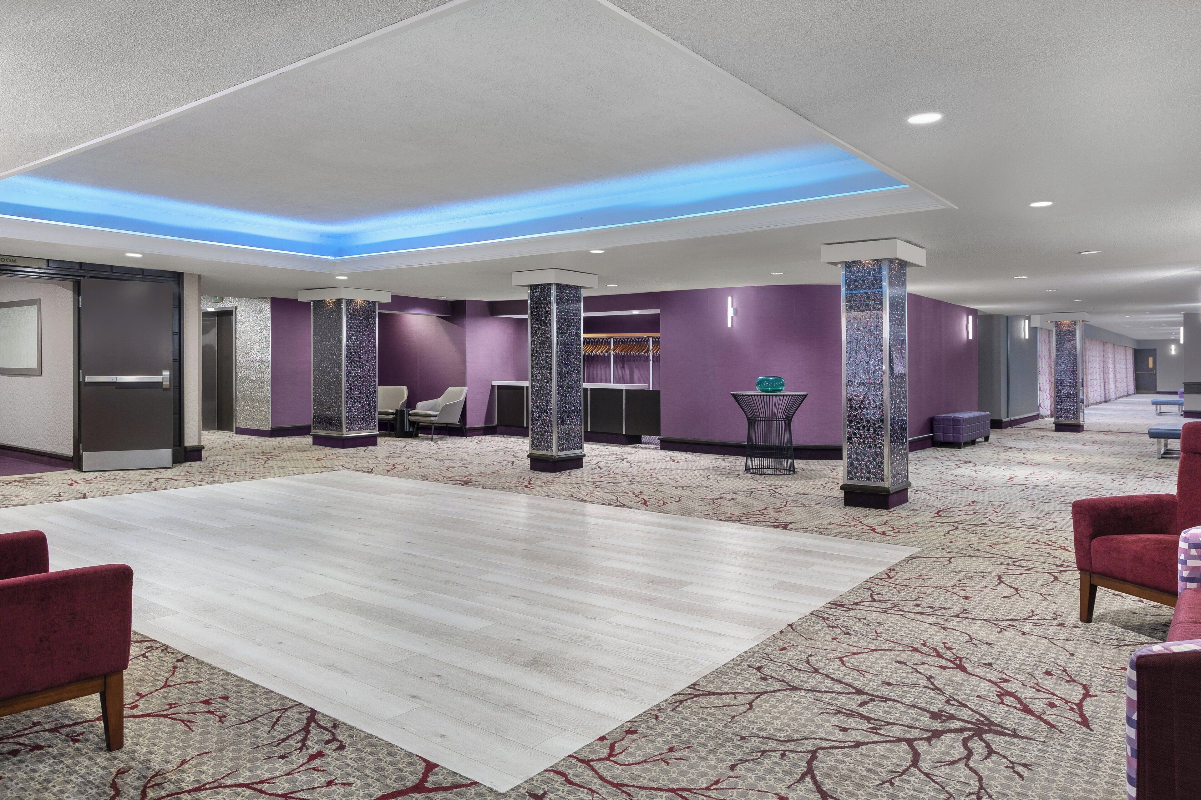 Un hall d’hôtel doté d’un grand comptoir d’accueil, d’un espace salon et d’un tapis à motifs.