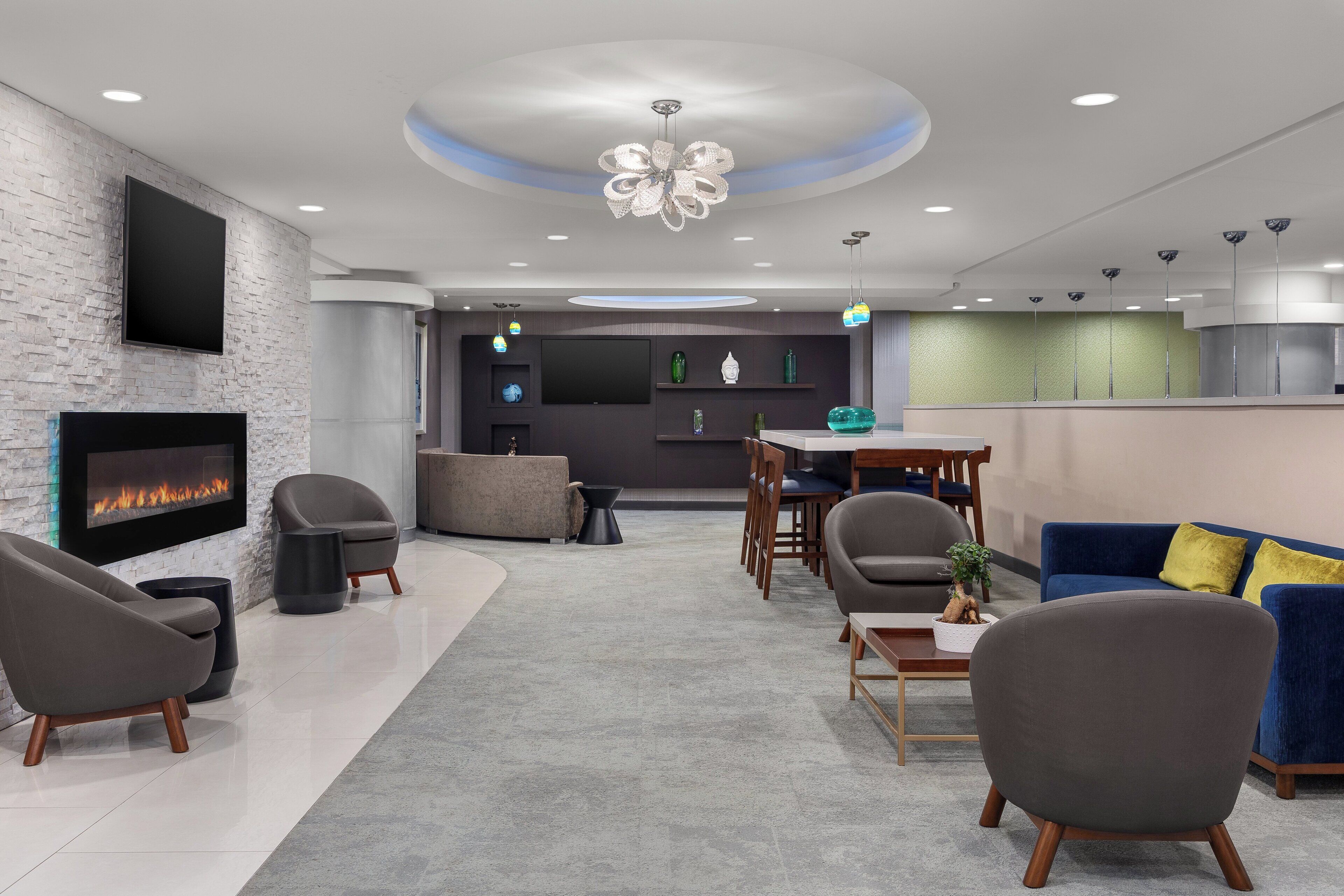 A modern lobby with a fireplace, seating area, and a dining table.