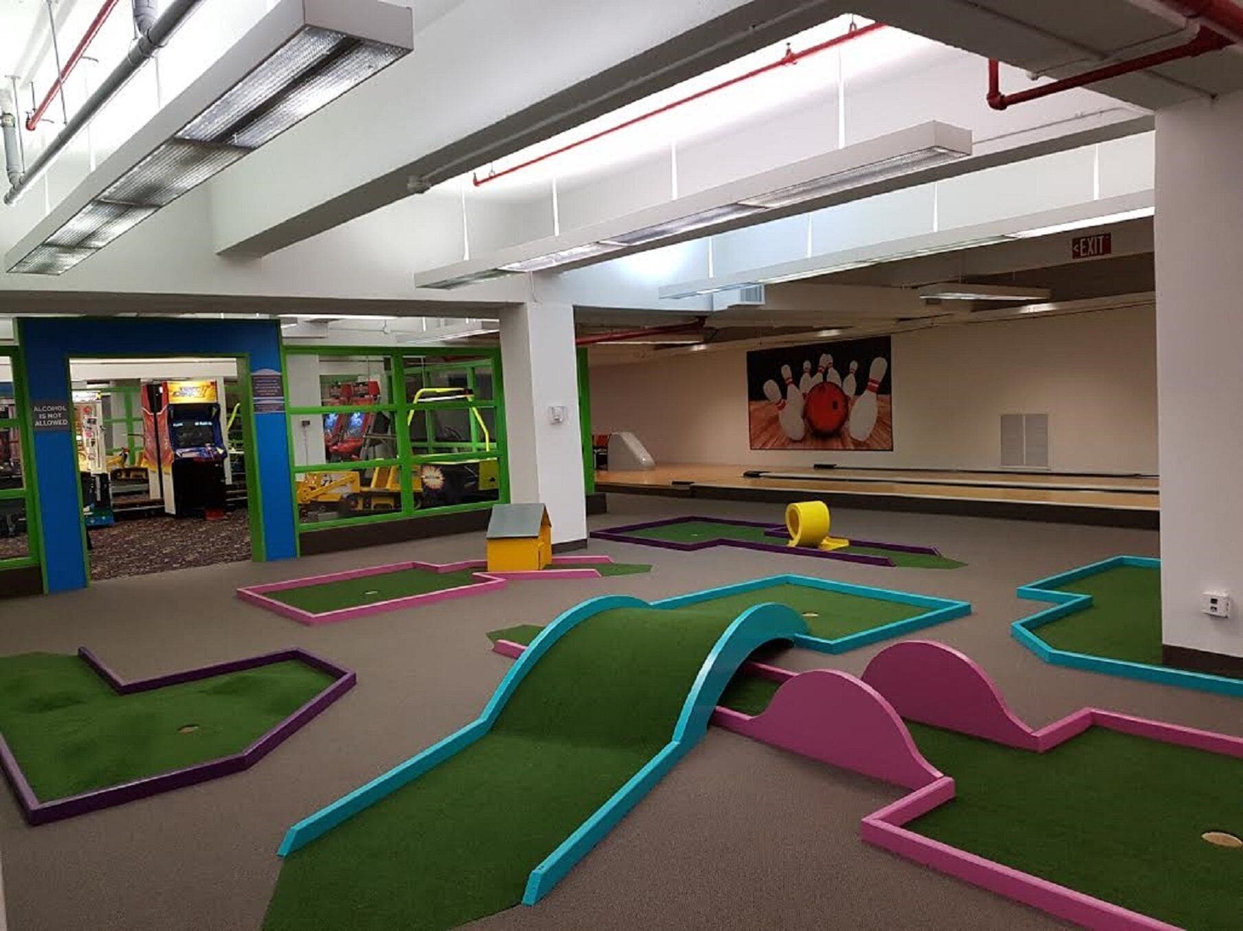 Une salle de bowling avec des pistes vertes, une boule de bowling et des quilles.