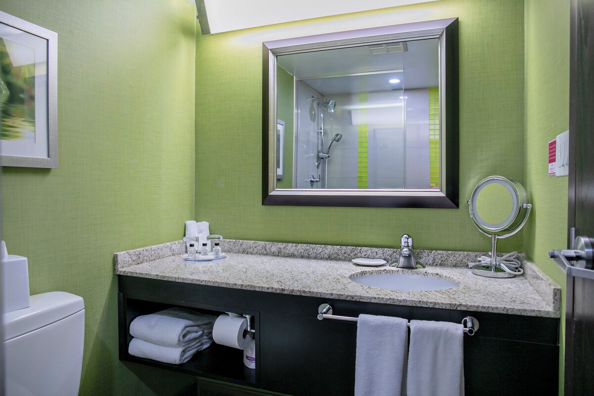 Une salle de bain équipée d’un lavabo, d’un miroir, d’un porte-serviettes et de toilettes.