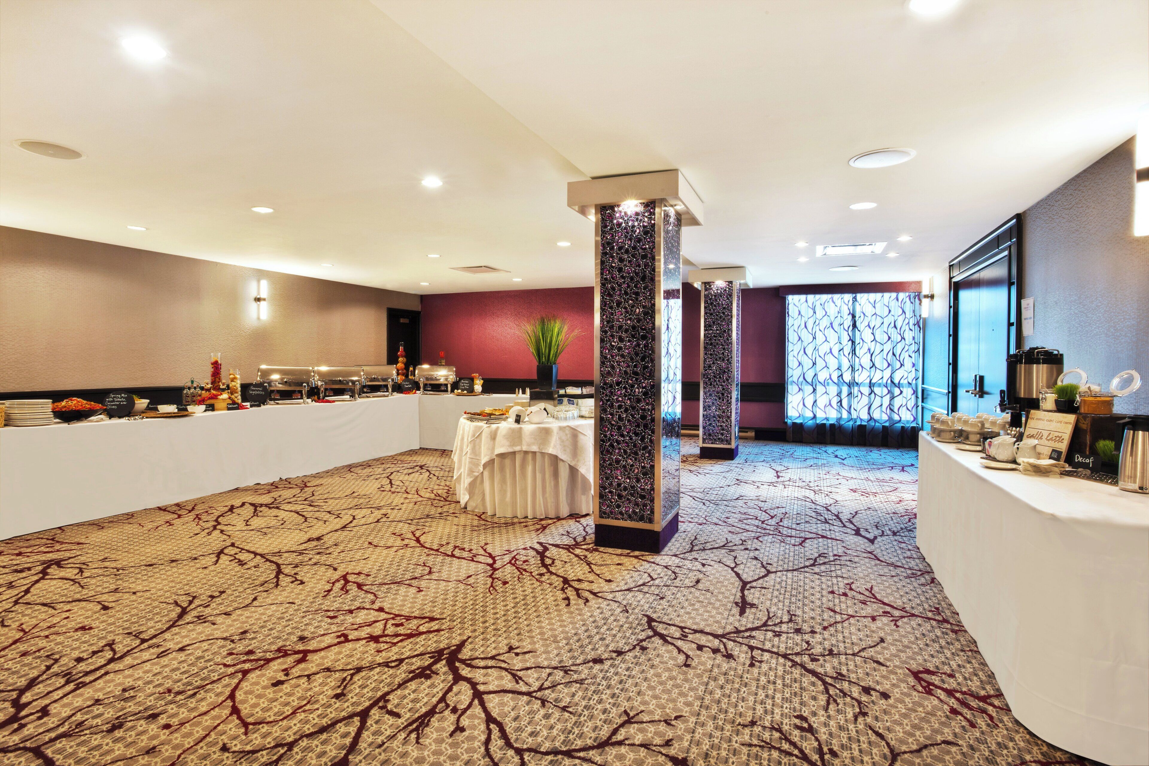 A hotel conference room with a buffet setup, a decorative pillar, and a patterned carpet.