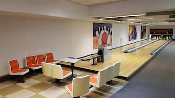 Een bowlingbaan met oranje en witte zitplaatsen, een bowlingbaan en een neerzetapparaat voor de bowlingpinnen.