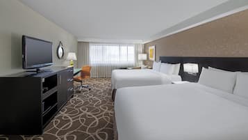 A hotel room with two beds, a TV, a desk, and a chair.