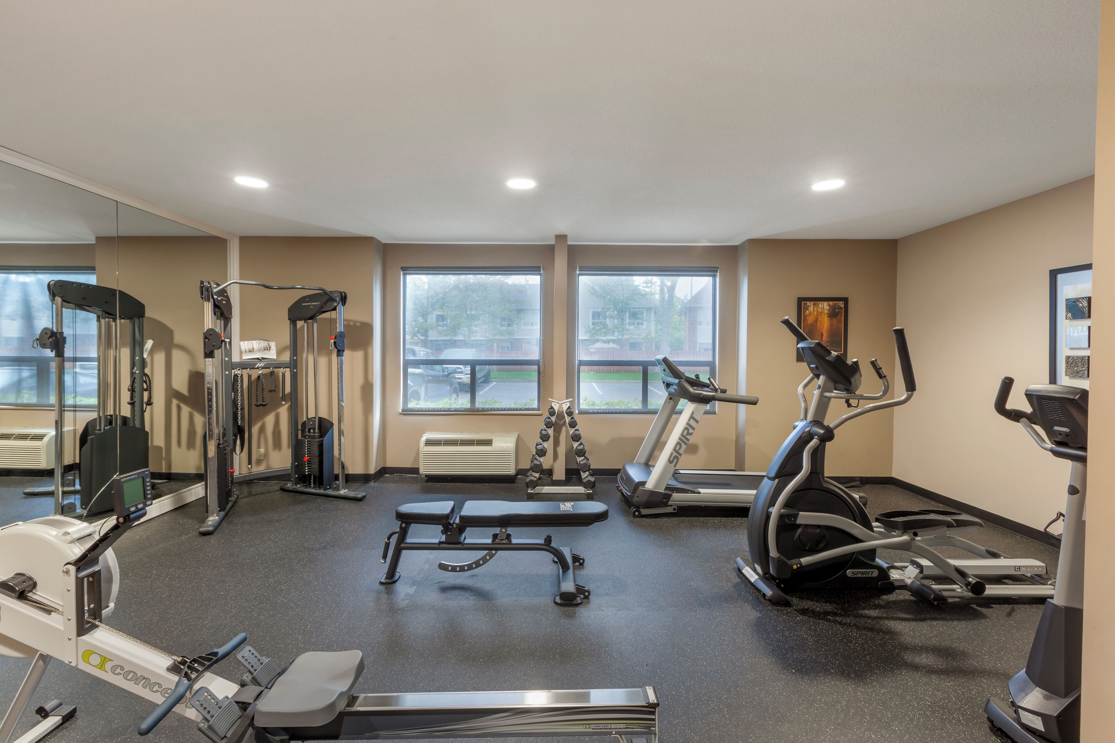 A gym with cardio machines, weight equipment, and a bench.