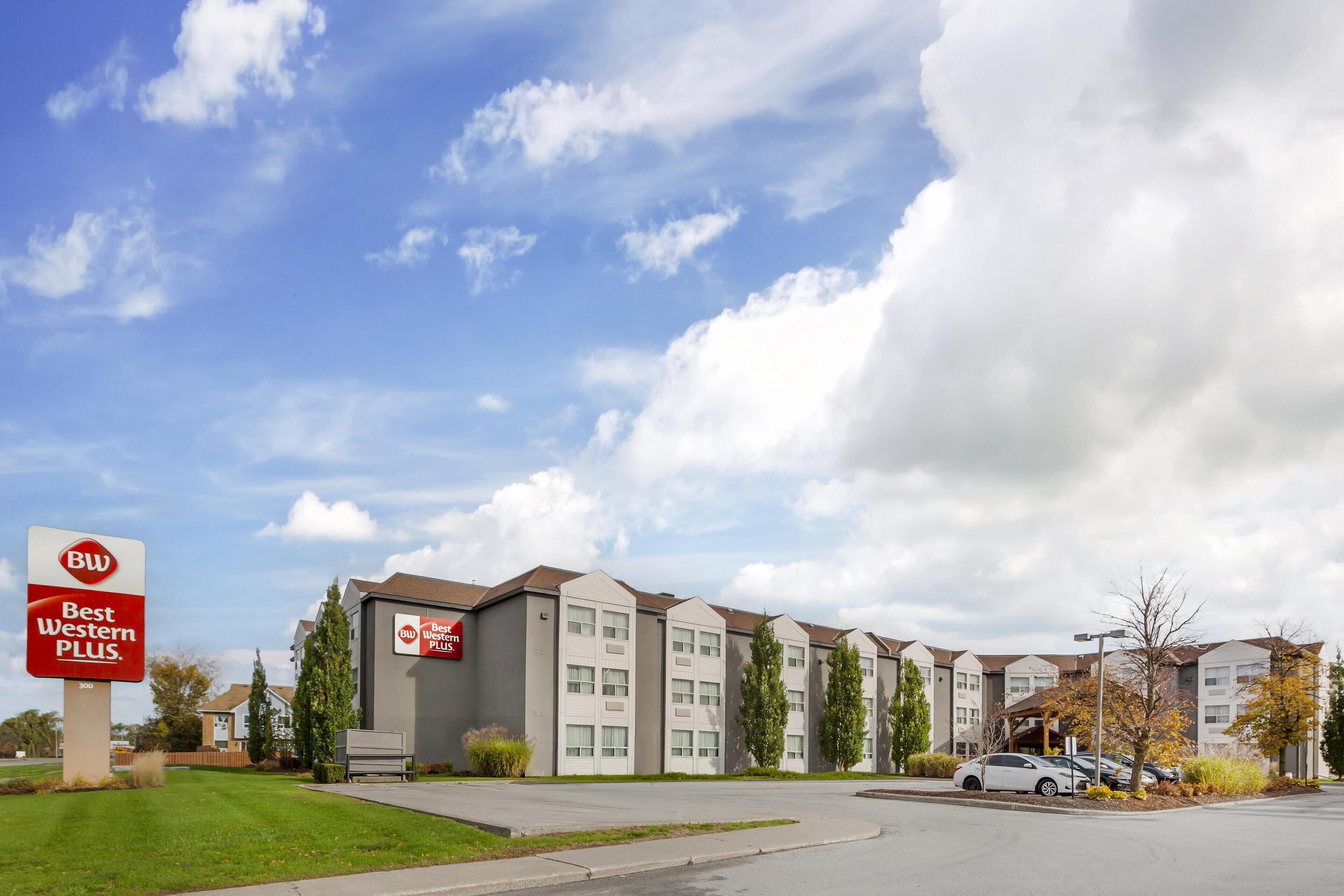 A Best Western Plus hotel with a modern architectural design, featuring a parking lot and a clear sky.