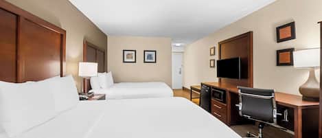 Habitación de hotel con dos camas, un escritorio, una silla, un televisor y un minibar.