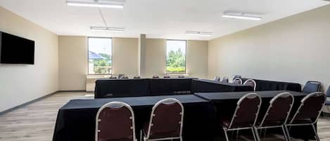 Un salón de conferencias con una larga mesa, sillas y ventanas grandes.