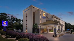 Um hotel Comfort Inn & Suites com design moderno, apresentando uma entrada notável e um jardim frontal ajardinado.