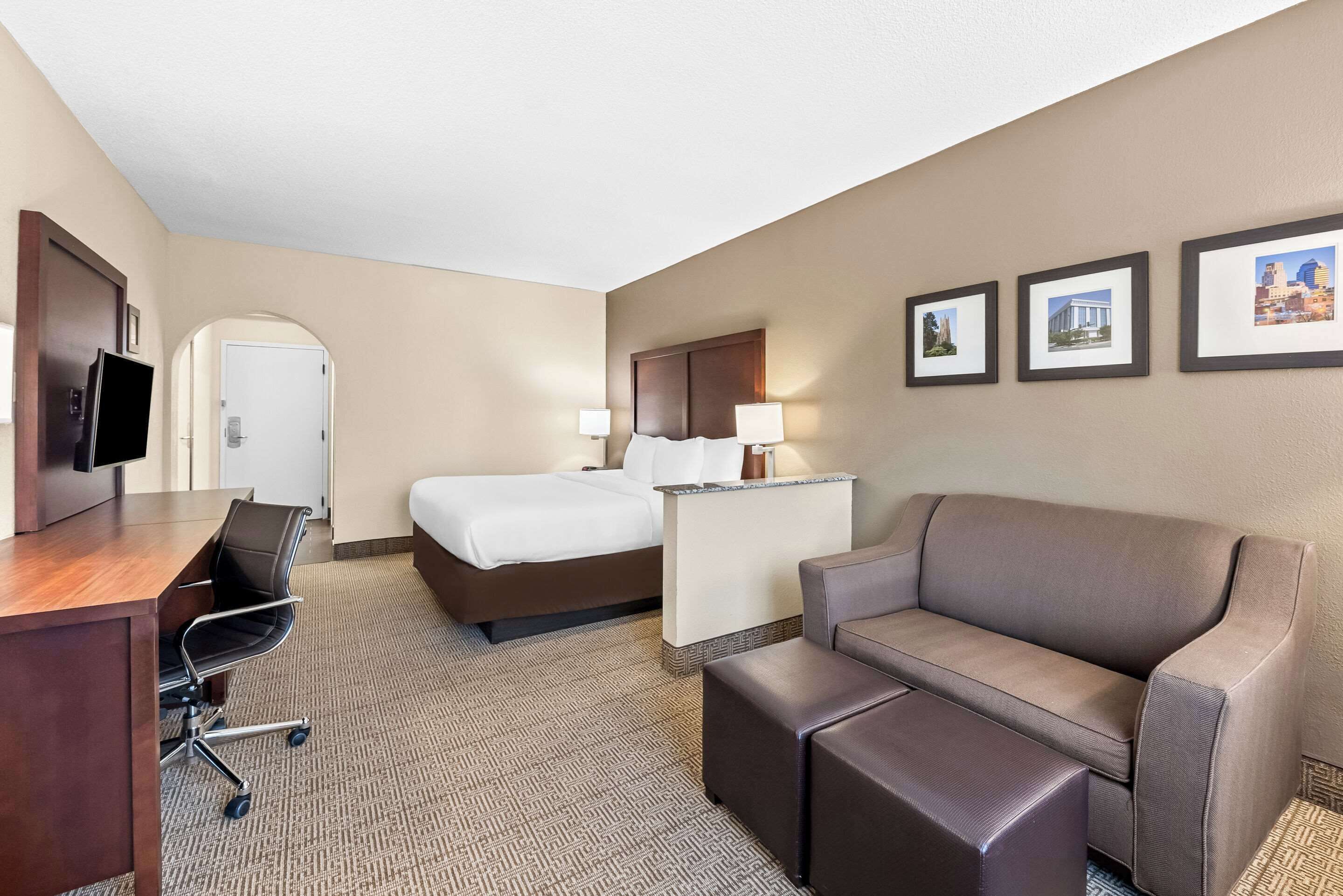 Une chambre d’hôtel équipée d’un lit, d’un bureau, d’une chaise, d’un canapé et d’une télévision.