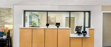 A reception desk with a modern design, featuring a wooden counter and glass panels.
