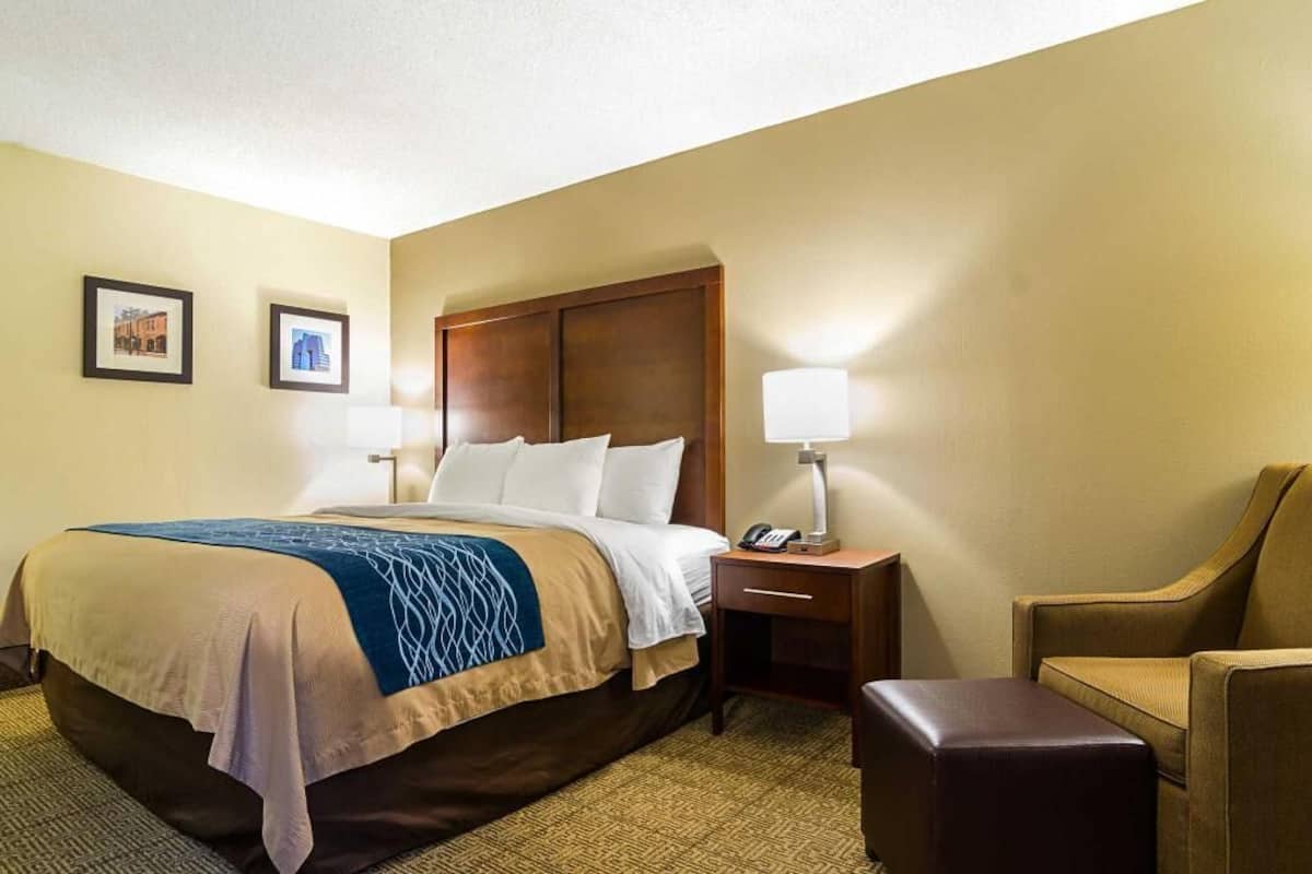Ein Hotelzimmer mit Bett, Nachttischen, einem Sessel und einer Lampe.