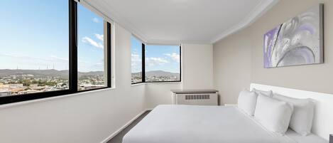 Habitación de hotel con una cama grande, vistas a la ciudad y una lámpara de techo.