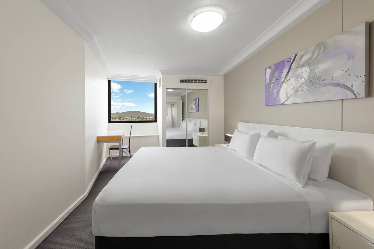 Una habitación de hotel con una cama grande, un escritorio y vistas a la ciudad.