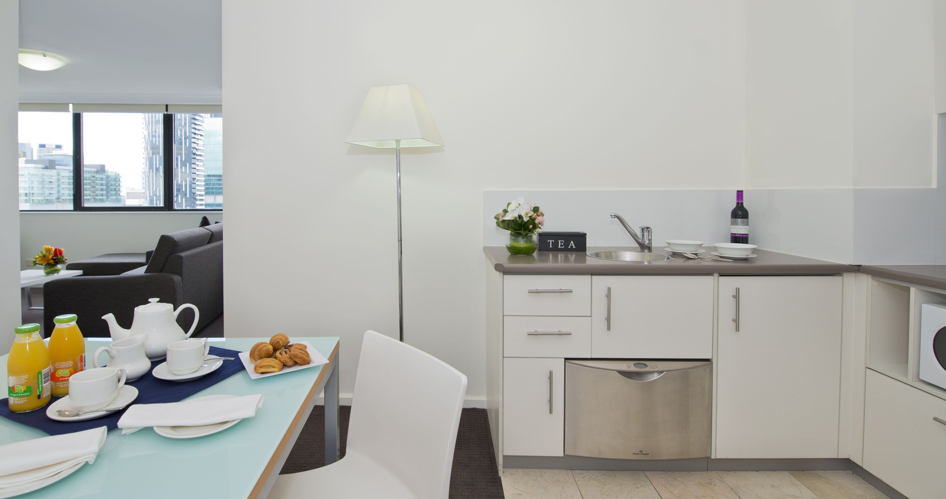 Una cocina moderna con comedor, que incluye una mesa dispuesta con alimentos para el desayuno, una cafetera y un cartel que indica té.
