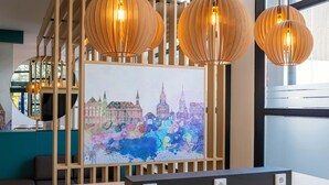 Een moderne hotelkamer met een houten scheidingswand, een schilderij van een stadsgezicht en drie bolvormige hanglampen.