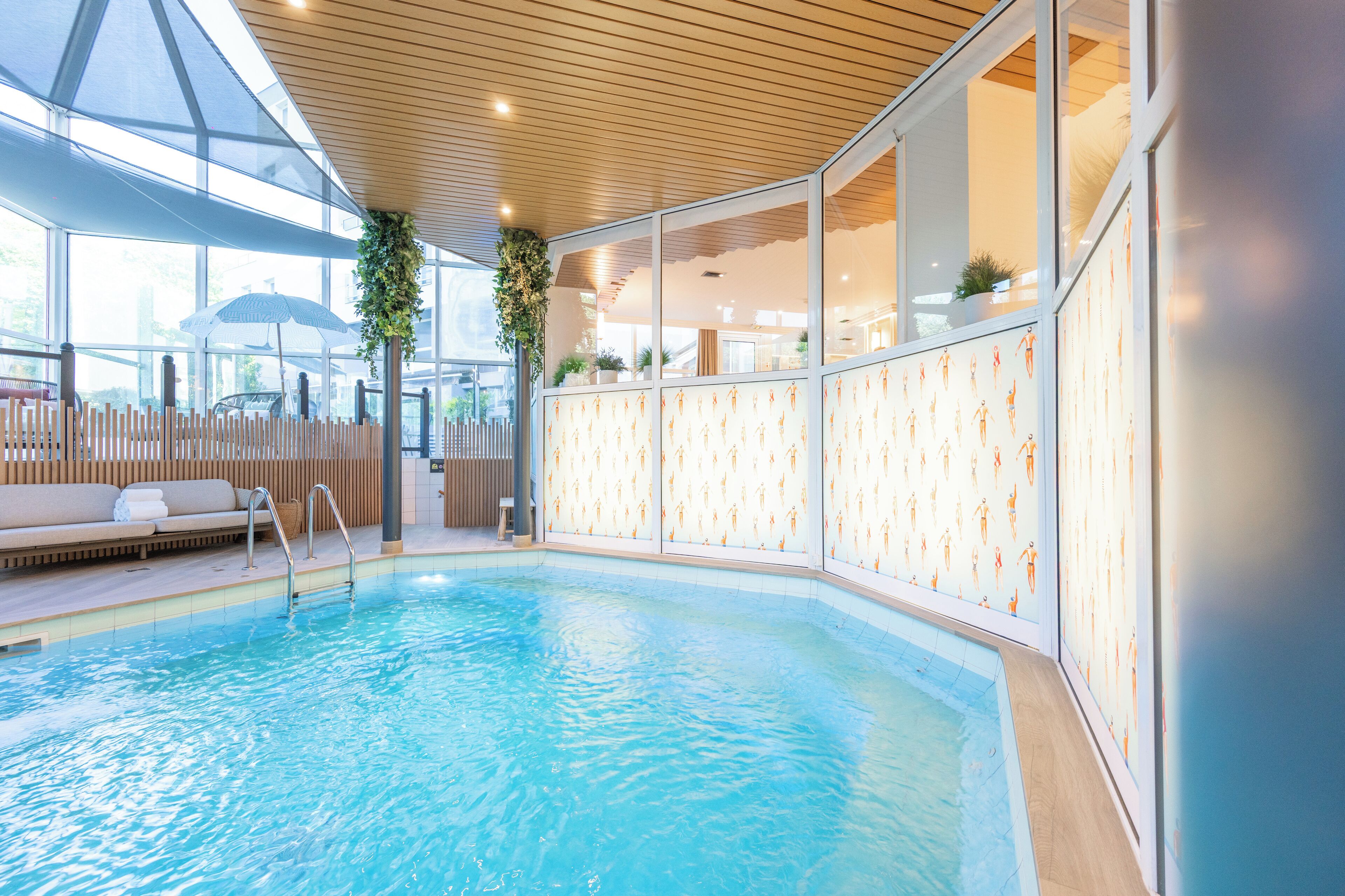 Ein Schwimmbecken mit Holzterrasse, Liegebereich und Glaswänden mit Übungsanleitungen.
