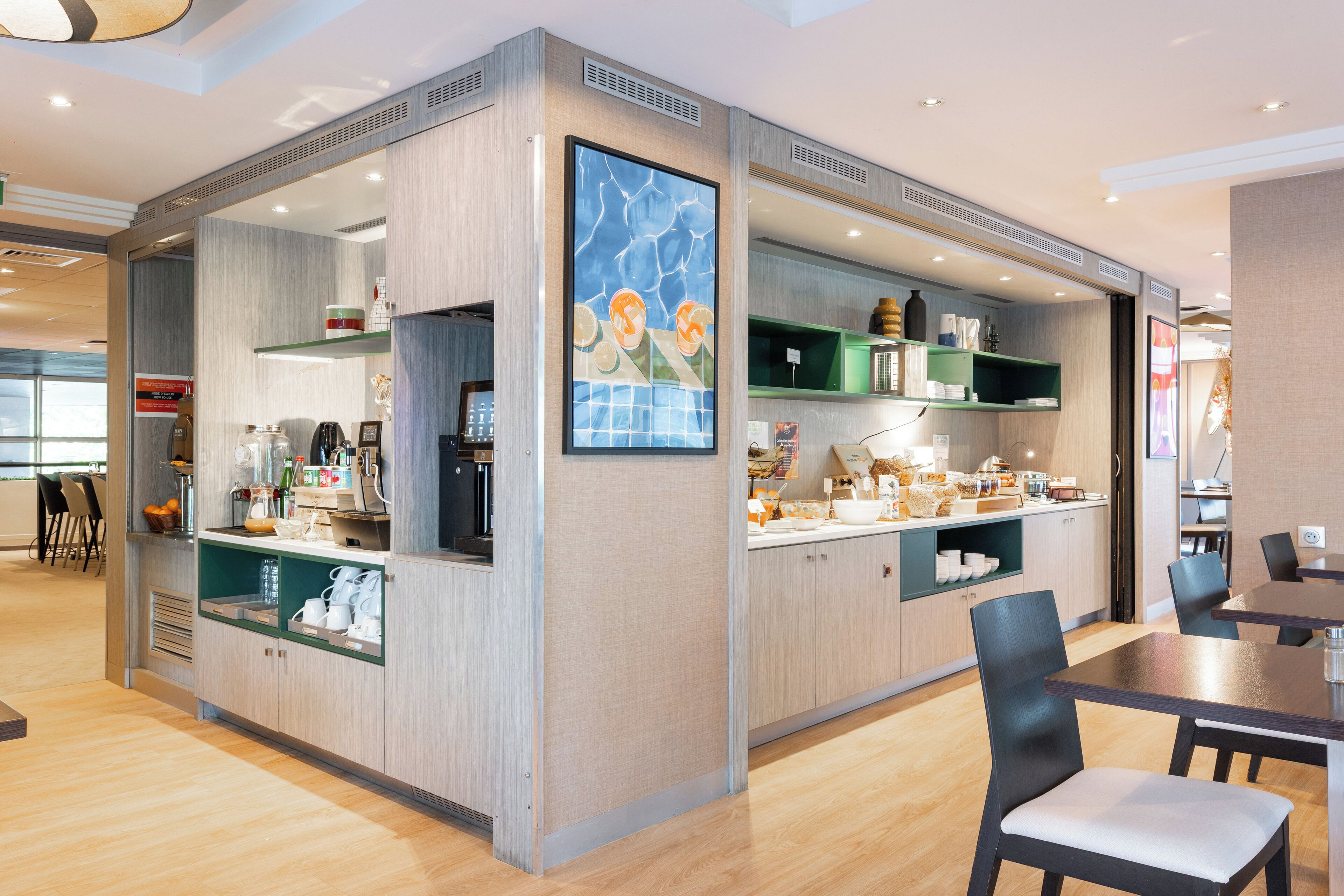 Una cafetería moderna con mostrador de madera, zona de estar y un cuadro grande en la pared.
