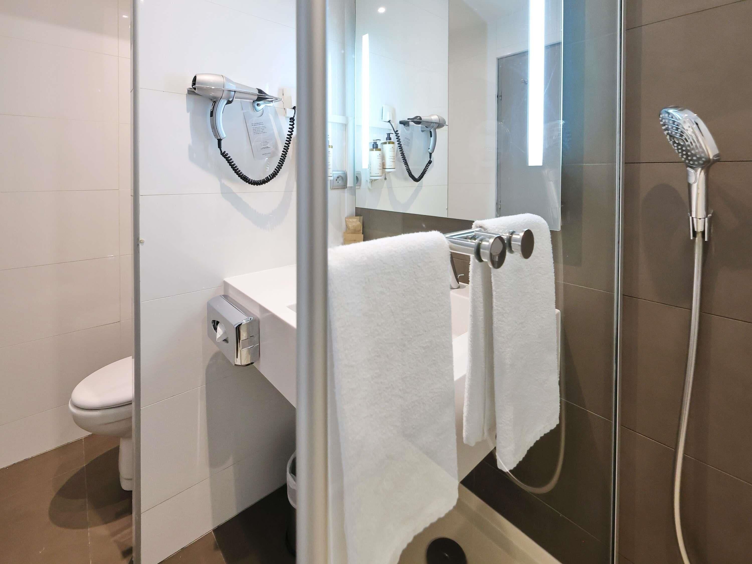Un bagno moderno con il water, un lavabo, uno specchio e una doccia.