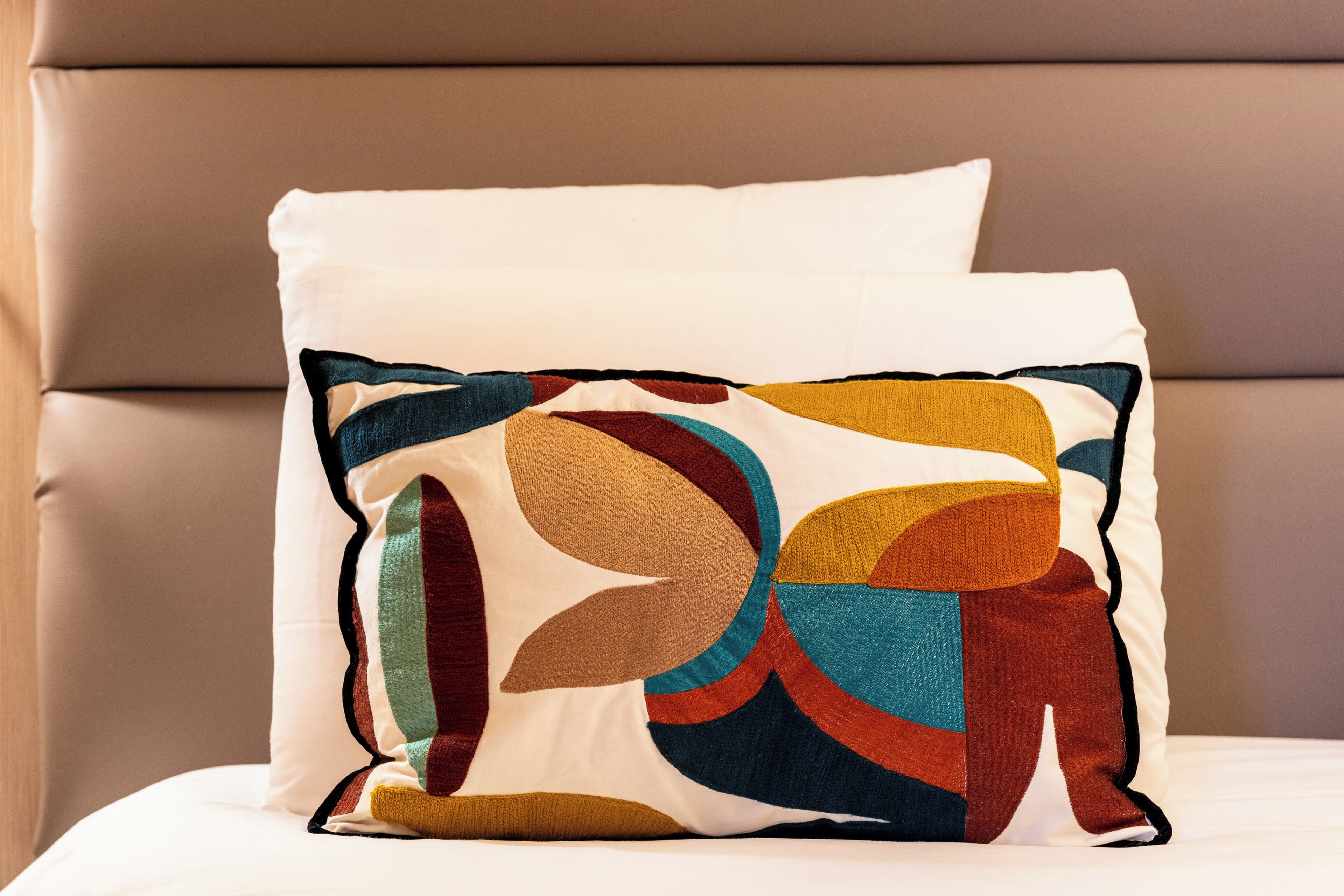 Almohada con un diseño abstracto y colorido sobre una cama.