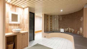 Une salle de bain moderne avec un meuble-lavabo en bois, un grand miroir et un coin salon agrémenté d’une fresque murale.