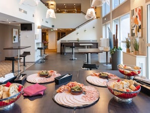 A buffet setup with various meats, cheeses, and bread in a modern hotel setting.