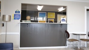 A reception area with a counter, chairs, and a sign indicating smoking rooms are available. - Days Inn by Wyndham Monroe LA (Monroe)