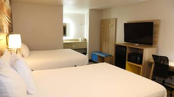 A hotel room with two beds, a television, a desk with a chair, and a microwave.