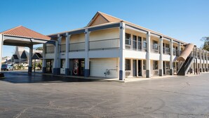 A two-story building with a covered entrance, a garage door, and a staircase leading to an upper level. - Days Inn by Wyndham Monroe LA (Monroe)