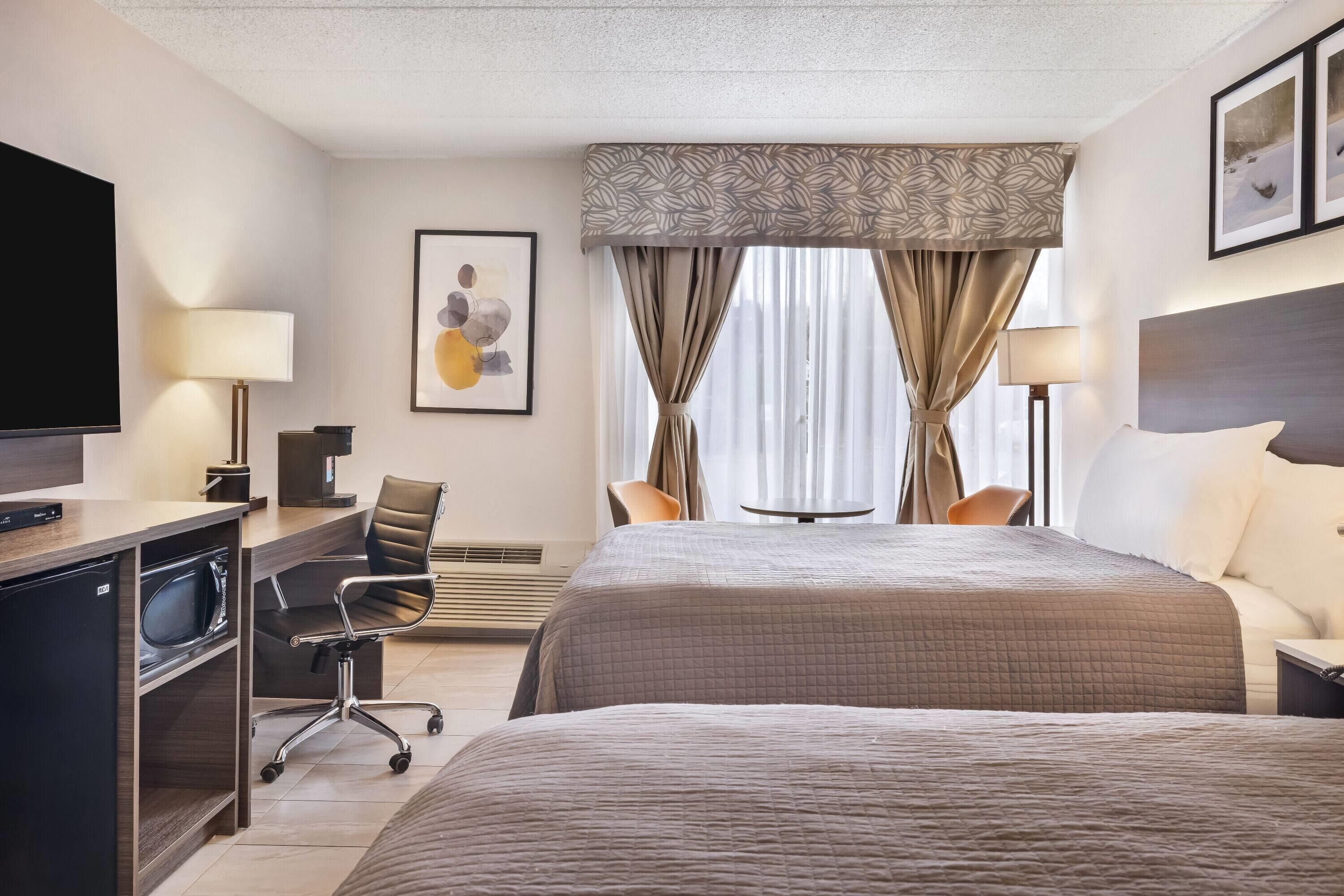 Una habitación de hotel con cama, escritorio, silla, televisión y obras de arte.