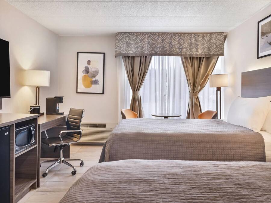 Una habitación de hotel con cama, escritorio, silla, televisión y obras de arte.