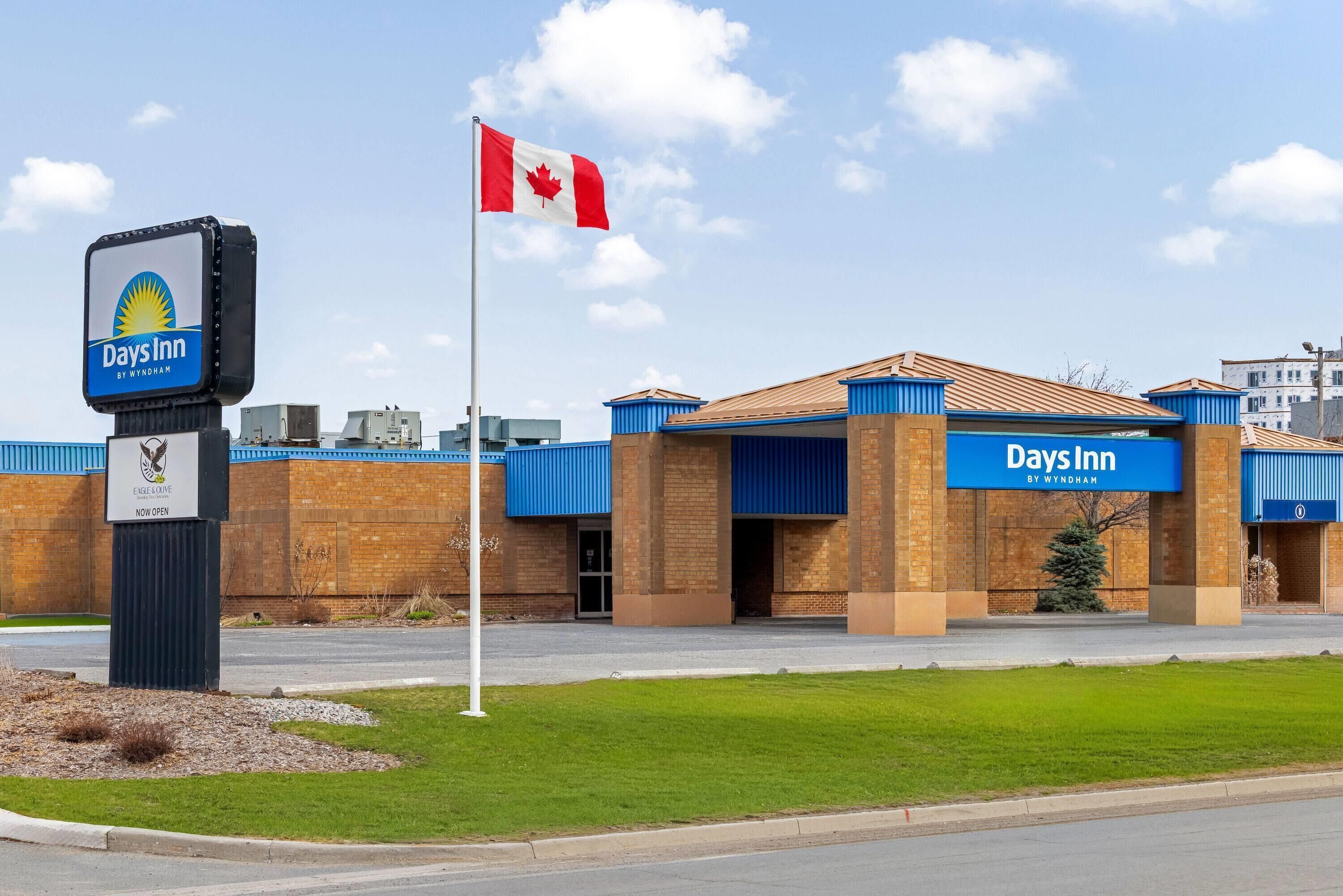 Edificio Days Inn con una bandera canadiense, un cartel y un toldo azul.