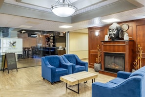 Un hall d’entrée avec des canapés bleus, une cheminée en bois et une statue de Bouddha.