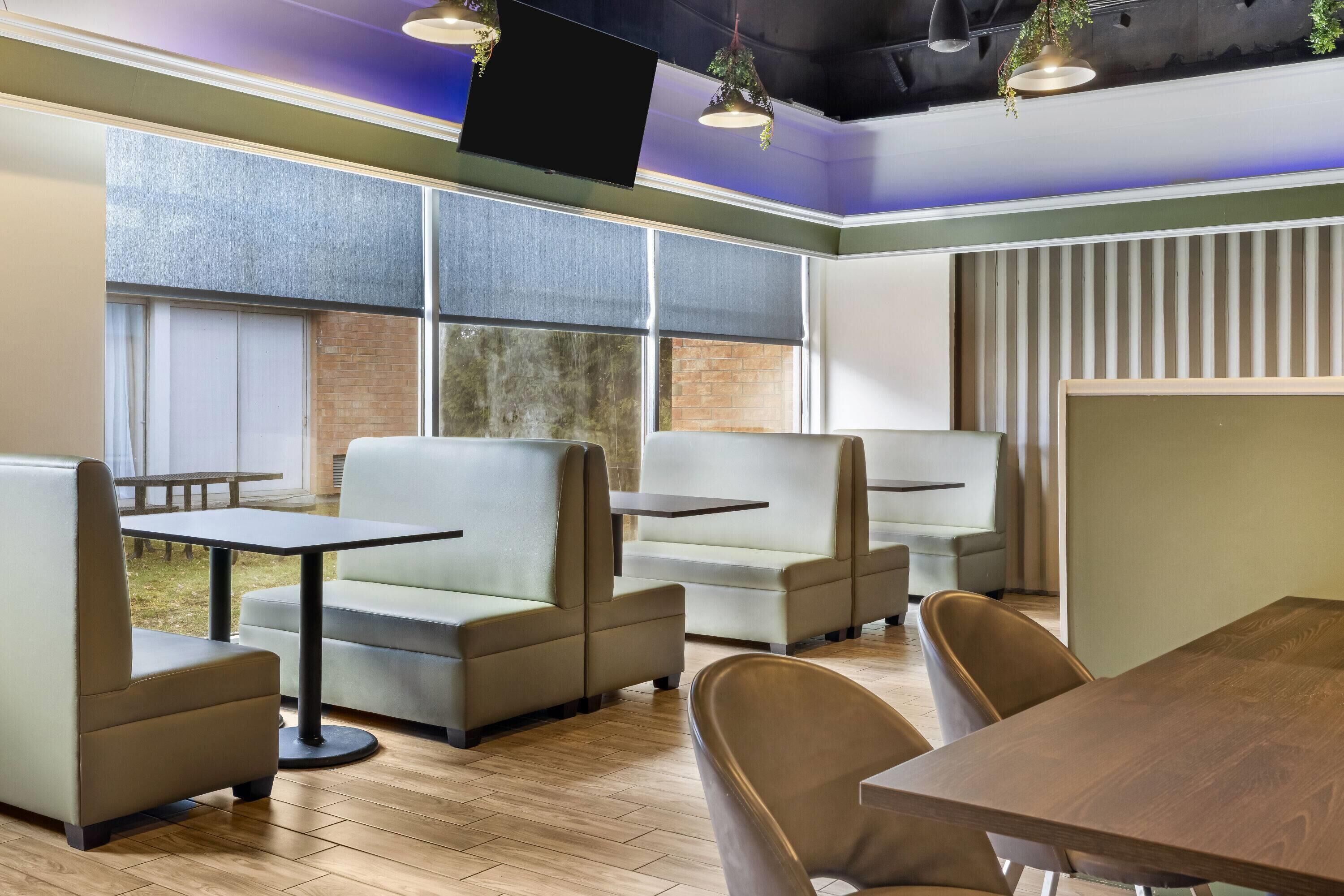 A modern interior with seating arrangements, tables, and large windows.