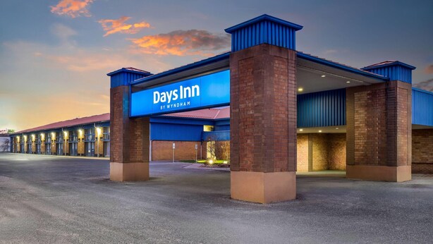 A Days Inn by Wyndham with a brick facade, large signage, and a covered entrance.