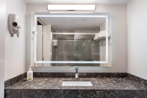 Une salle de bain avec un grand miroir, un sèche-cheveux, un savon Dove et un lavabo en marbre.