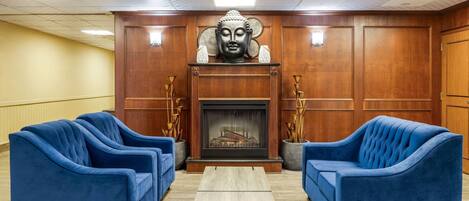 Una habitación con dos sofás azules, una mesa de centro de madera, una estatua de Buda y una chimenea.