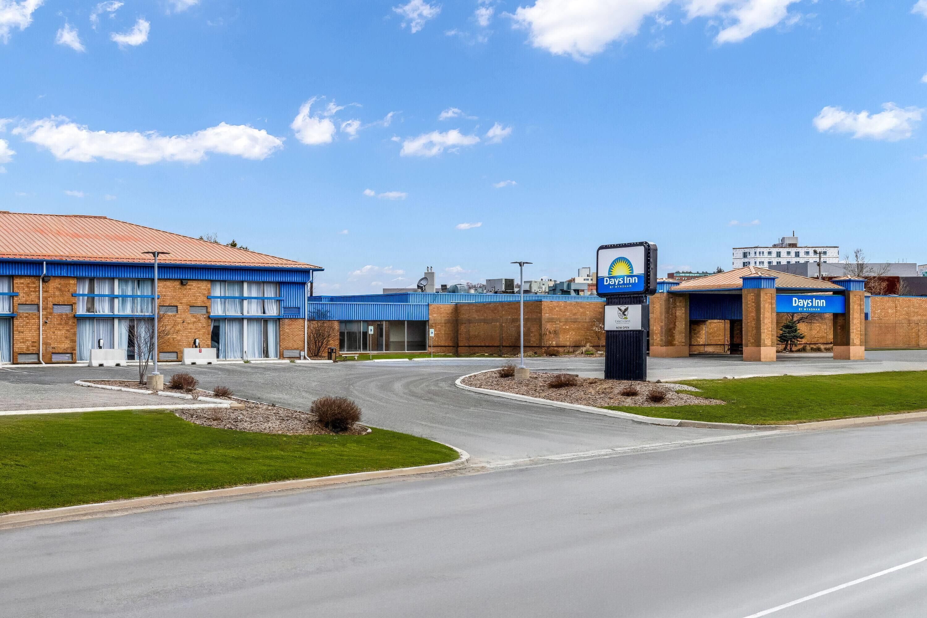 A Days Inn with a brick facade, a blue awning, and a clear sky.