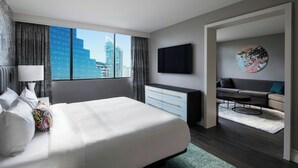 Una habitació d'hotel moderna amb un llit gran, un escriptori, un televisor de pantalla plana i un sofà.
