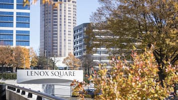 A sign for Lenox Square with modern buildings in the background.