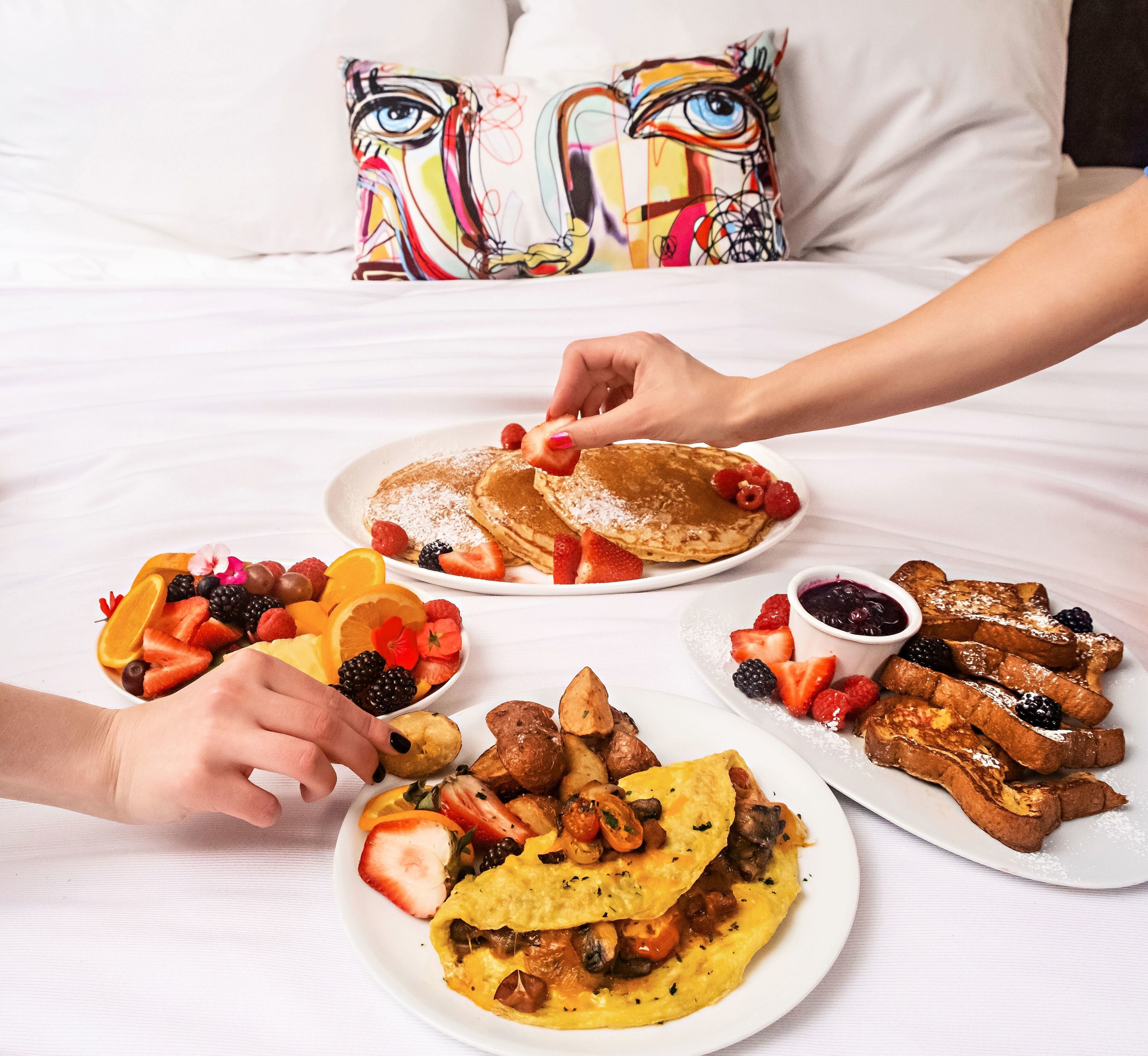 Una mesa de desayuno con tortitas, gofres y tortillas, acompañadas de frutas y bayas frescas.