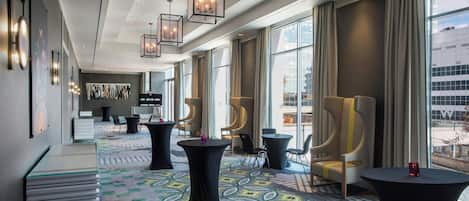 Un moderno vestíbulo de hotel con un largo pasillo, ventanas amplias y mobiliario contemporáneo.