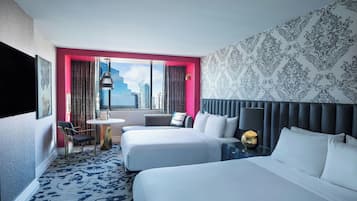 A hotel room with two beds, a small table, a chair, and a view of the city skyline.