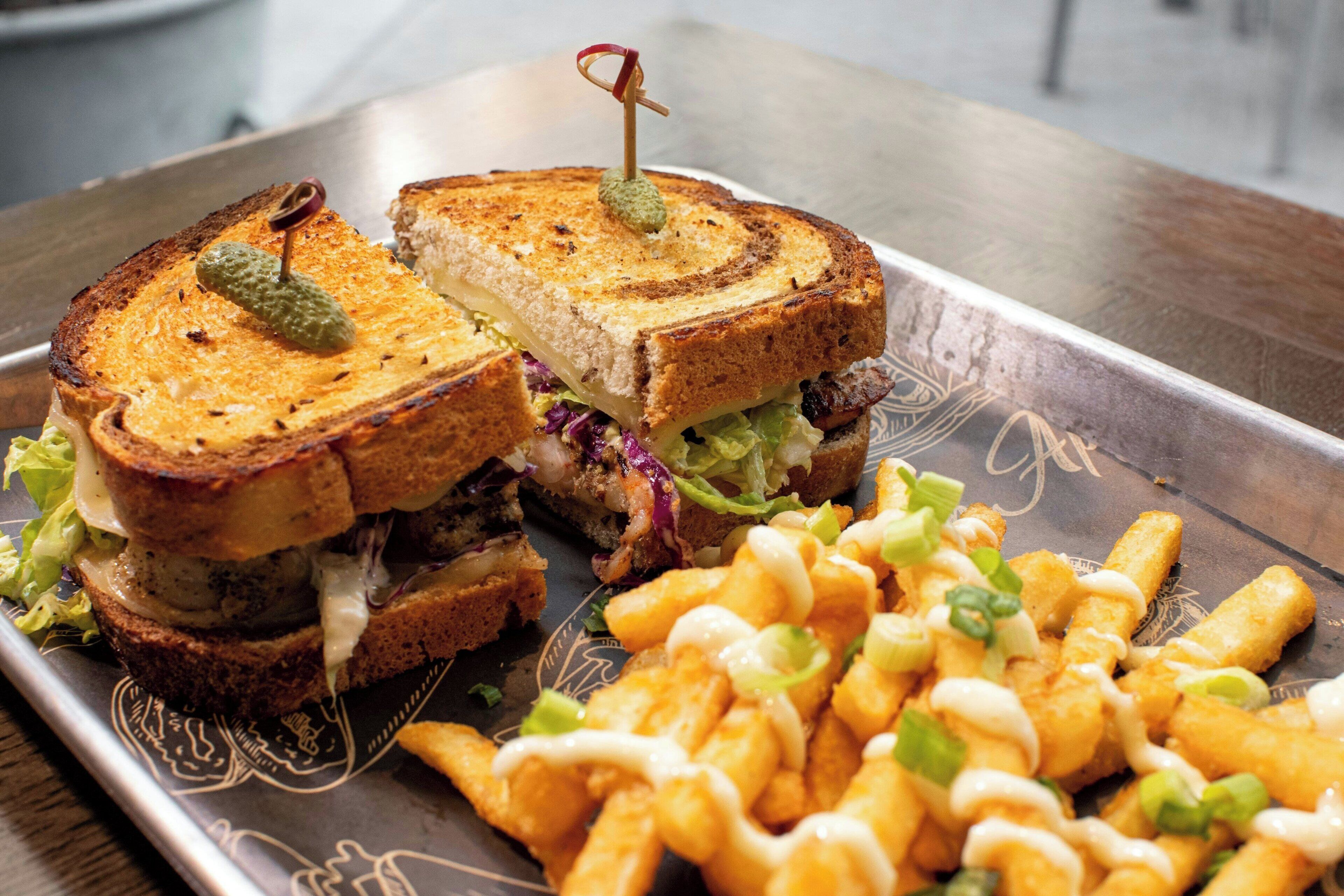 A sandwich with a toothpick, lettuce, and a side of fries.