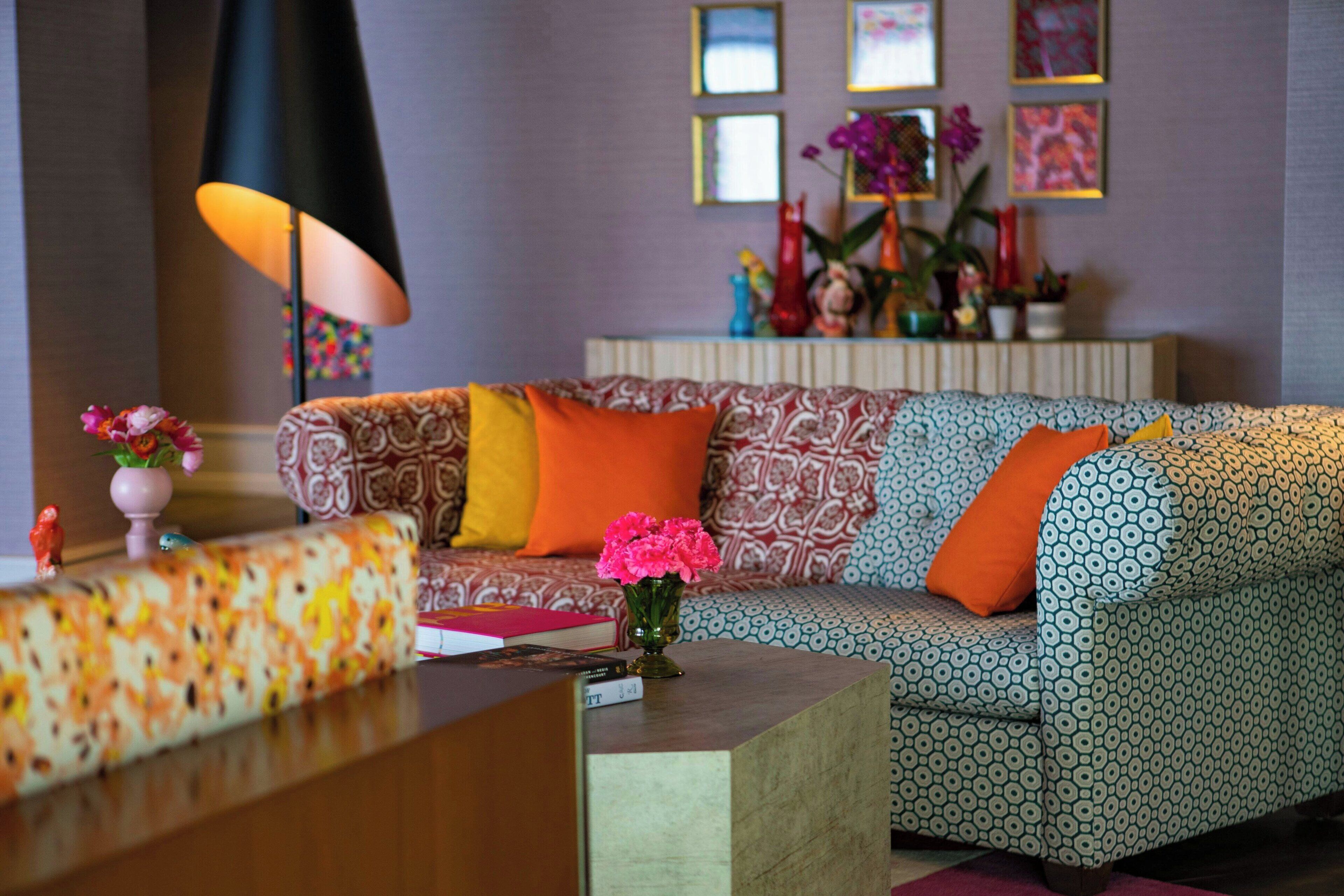 A modern living room with patterned sofas, a coffee table, and a vase of flowers.