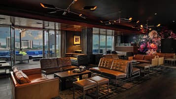 A modern lounge with leather sofas, a fireplace, and large windows offering city views.