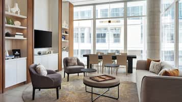 A modern living room with a sofa, armchairs, a coffee table, and a dining area with chairs and a table.