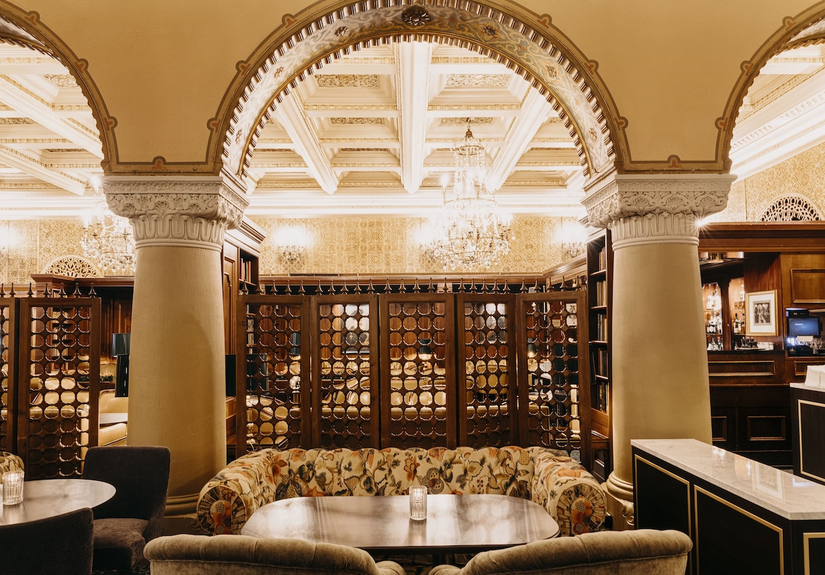 Ornate archways with a lot of carved detailing, coffered ceiling, with couch seating
