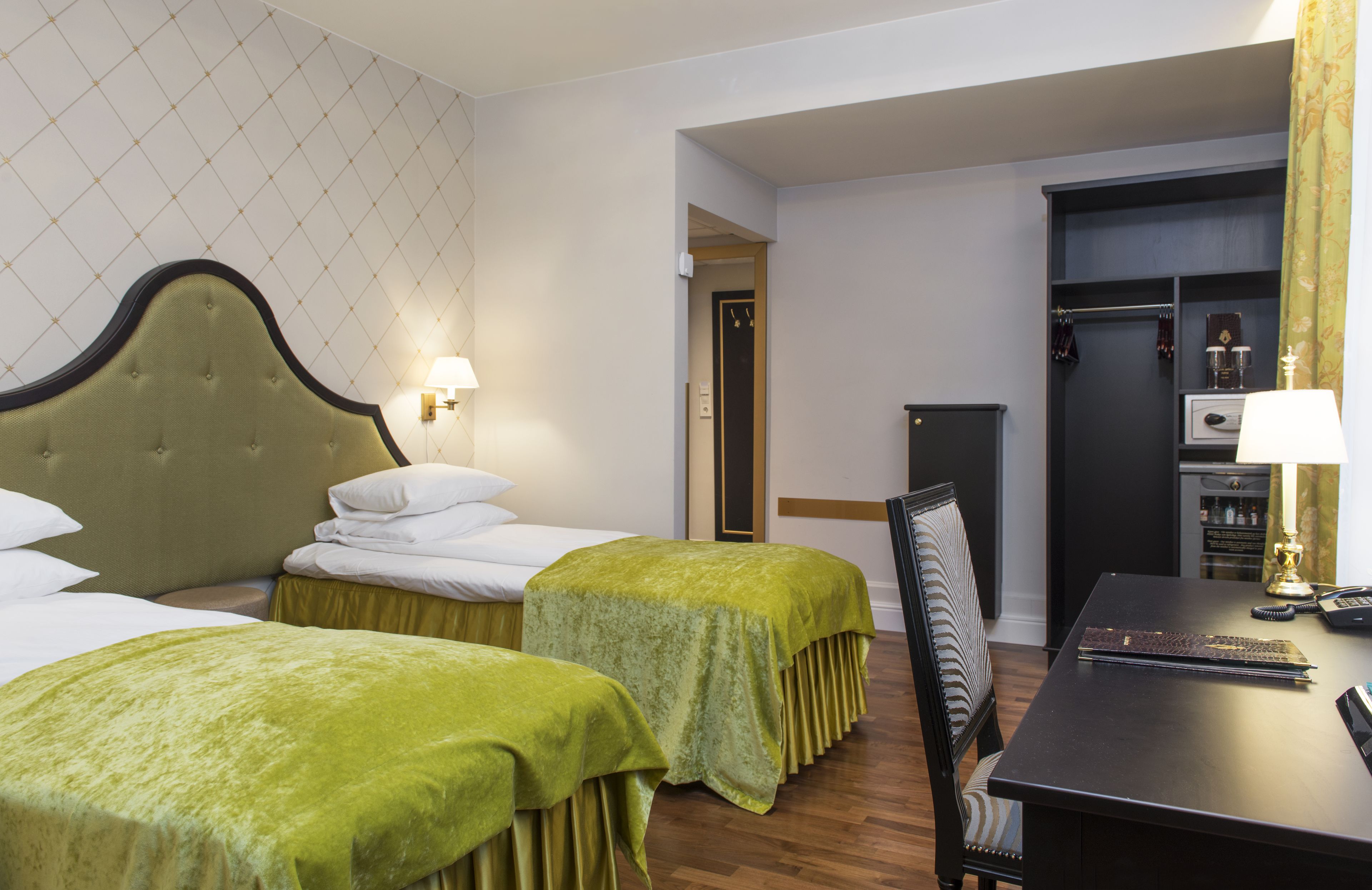 Camera d'albergo con due letti, una scrivania e un armadio.