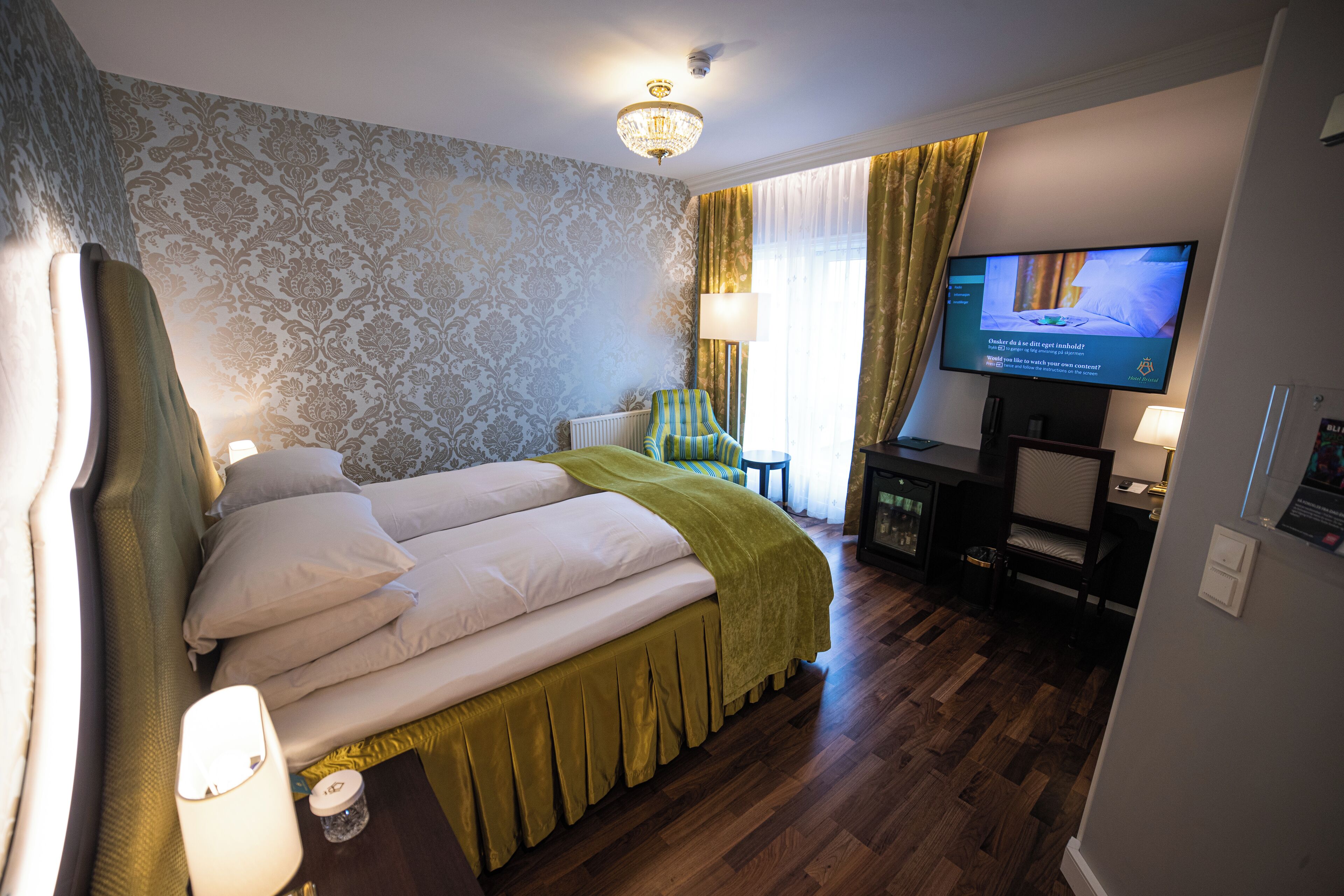 Une chambre d’hôtel avec un grand lit, une télévision, une chaise et un bureau.