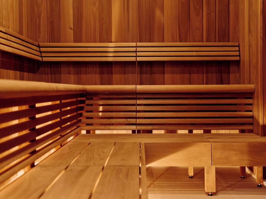 Una sauna de madera con bancos y piso de baldosas.